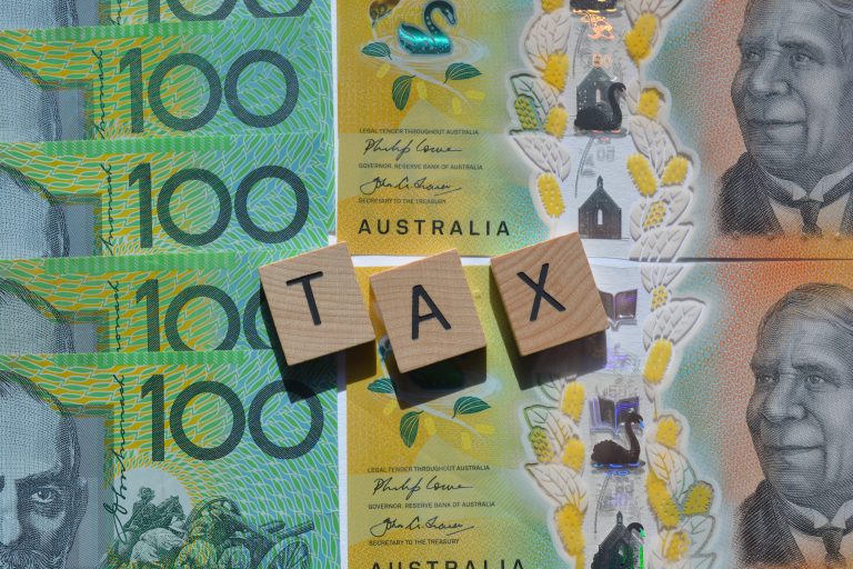 tax word in wood letters on top of Australian dollars
