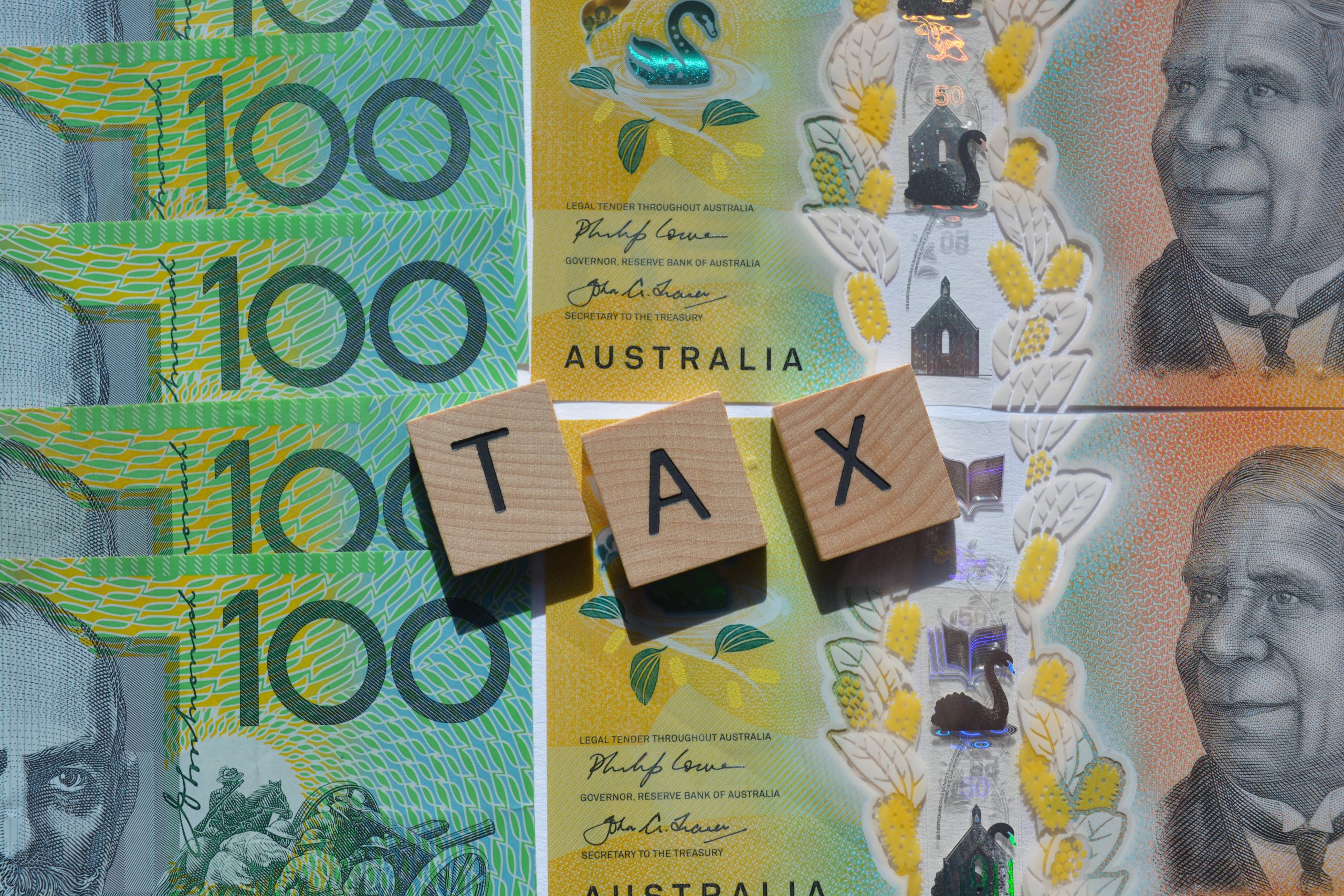 tax word in wood letters on top of Australian dollars