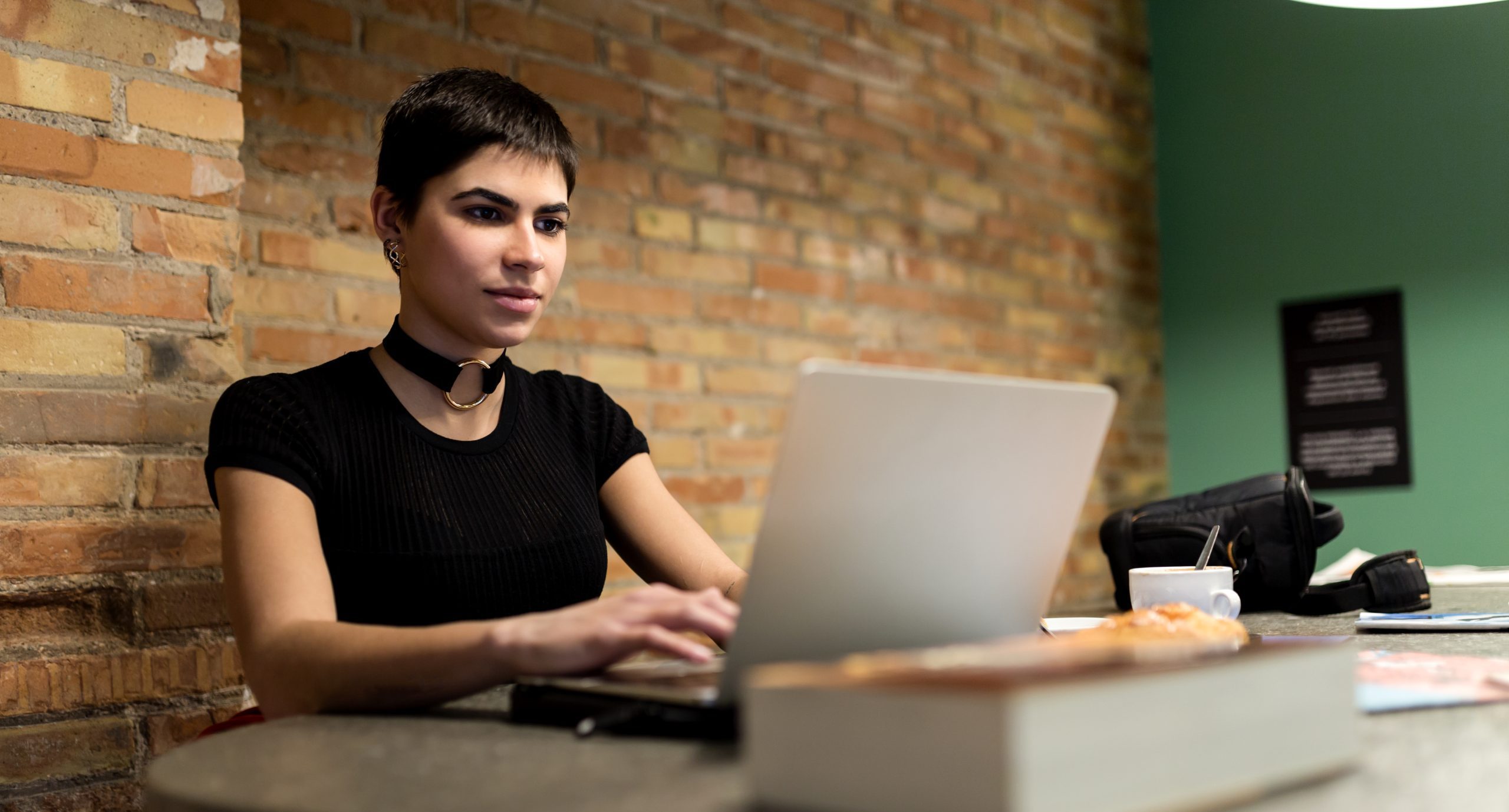 Young woman browsing a laptop in a cafe.